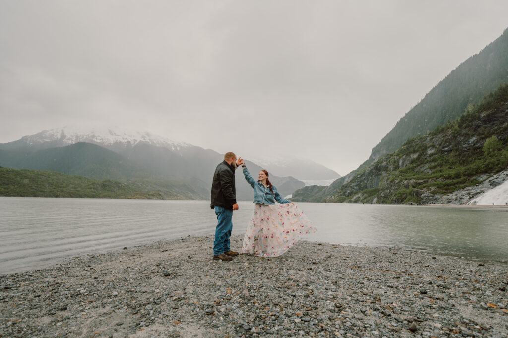 Man and woman dancing on the beach with the mountain behind