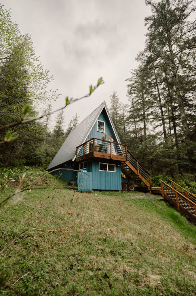 couple stand on the deck at Alaska A-frame Airbnbs