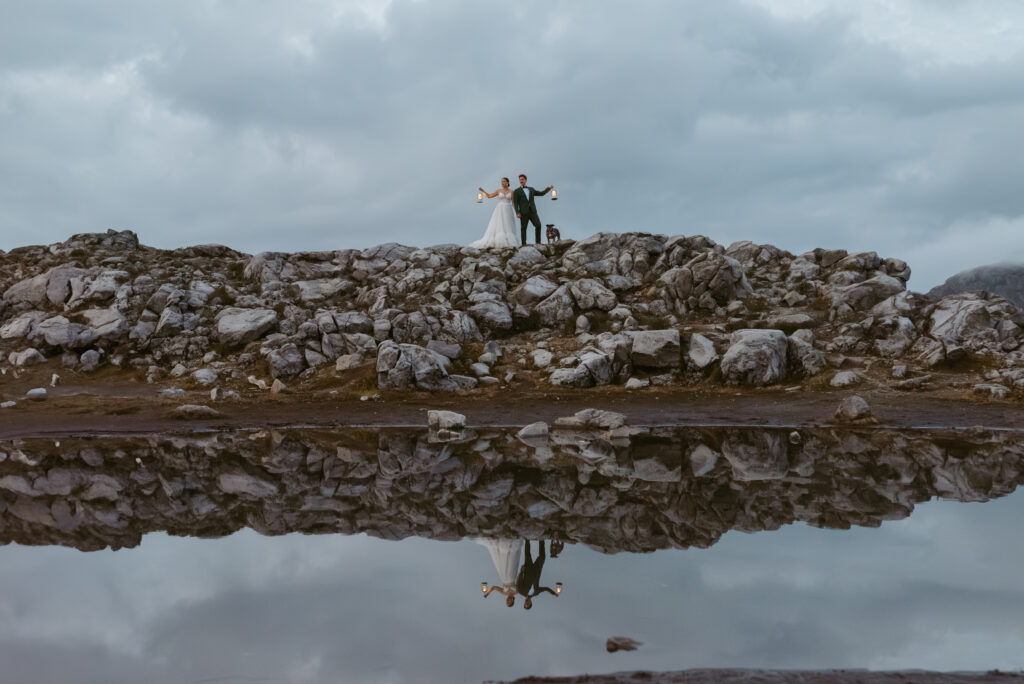 couple stand on rock with the reflections from the lake