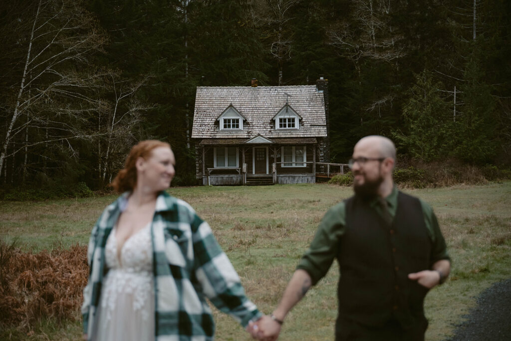 Lake Crescent Ranger's Cabin in the background with the couple smiling at eachother